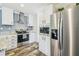 Modern kitchen with stainless steel appliances, white cabinetry, granite countertops, and wood grain flooring at 25126 Huston St, Brooksville, FL 34601