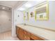 Bright bathroom featuring a vanity with wooden cabinets, gold-framed mirrors, and a toilet behind an open doorway at 2617 Cove Cay Dr # 401, Clearwater, FL 33760