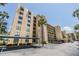 Exterior view of a multi-story beige apartment building with palm trees and covered parking at 2617 Cove Cay Dr # 401, Clearwater, FL 33760