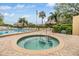 Tranquil hot tub with brick trim, next to a pool, featuring seating, palm trees, and an American flag at 2617 Cove Cay Dr # 401, Clearwater, FL 33760
