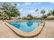 Large rectangular pool with brick trim, surrounded by lounge chairs, palm trees, and tiki huts at 2617 Cove Cay Dr # 401, Clearwater, FL 33760