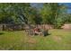 Landscaped backyard featuring a rustic fire pit, lush grass, mature trees, and a privacy fence at 267 Broad St, Brooksville, FL 34604