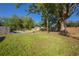 Spacious backyard featuring green grass, mature trees, a wood fence, and an open patio area at 267 Broad St, Brooksville, FL 34604