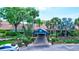Main entrance of the community center with lush landscaping, palm trees, and a covered walkway at 2961 Briar Cliff Dr, Palm Harbor, FL 34684