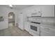 Bright kitchen includes white appliances and cabinetry, tile flooring, and a view to the bonus room at 306 S Highland Ave, Clearwater, FL 33755