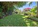 Expansive backyard featuring a well-maintained lawn, mature trees, and colorful flowering plants at 3501 S Drexel Ave, Tampa, FL 33629