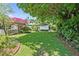 Spacious backyard with green lawn, mature trees, and vibrant flowers offering a private outdoor retreat at 3501 S Drexel Ave, Tampa, FL 33629