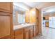 Bathroom vanity with wood cabinets, a large mirror, and a view towards the kitchen, enhancing the open feel at 3823 N 56Th St, Tampa, FL 33619