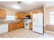 Bright kitchen showcasing light wood cabinetry, a tiled floor, and white appliances, including a refrigerator and range at 3823 N 56Th St, Tampa, FL 33619