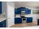 Modern kitchen features blue cabinets, stainless steel appliances, and light countertops at 4997 W Breeze Cir, Palm Harbor, FL 34683