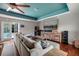 Open living room with hardwood floors, media center, ceiling fan, and plush sectional at 4997 W Breeze Cir, Palm Harbor, FL 34683