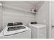 Clean laundry room featuring a modern washer and dryer with overhead shelving at 5276 6Th N Way, St Petersburg, FL 33703