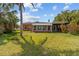 Exterior of house with a large grassy backyard and mature palm trees at 543 Crystal Dr, Madeira Beach, FL 33708