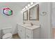 Bathroom with a double sink vanity, decorative mirror, and a unique stained-glass window at 581 Oceanview Ave, Palm Harbor, FL 34683