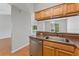 Modern kitchen area featuring wooden cabinetry, stainless steel dishwasher, and a view to the living room at 581 Oceanview Ave, Palm Harbor, FL 34683