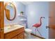 Charming powder room with flamingo wall decor, a unique mirror, and shelving for storage at 5816 Dory Way, Tampa, FL 33615