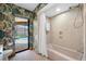 Bathroom features a tub with a shower and tropical wallpaper, offering a unique design at 5816 Dory Way, Tampa, FL 33615