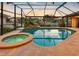 Relaxing pool and spa area inside a screened enclosure with a view of the waterfront and lush landscaping at 5816 Dory Way, Tampa, FL 33615