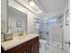 Bright bathroom featuring a marble tiled shower with a glass door and updated vanity with a framed mirror at 5821 Thrush Dr, New Port Richey, FL 34652