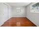 Clean bedroom with hardwood floors, a large window for natural light, and closet with sliding doors for storage at 5821 Thrush Dr, New Port Richey, FL 34652