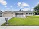 Charming single-story home featuring a well-manicured lawn, neutral paint, white picket fence, and an attached two-car garage at 5821 Thrush Dr, New Port Richey, FL 34652