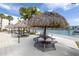 Waterfront picnic area featuring tiki hut umbrellas, tables, and a serene view of the water at 7625 Sun Island S Dr # 106, South Pasadena, FL 33707