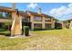 Rear view of a tan condo complex with lawns, landscaping, and stairs to upper units at 8005 Bardmoor Pl # 102I, Seminole, FL 33777