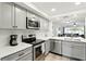 Stylish kitchen featuring gray cabinets, stainless appliances, and a view to the living room at 8005 Bardmoor Pl # 102I, Seminole, FL 33777