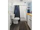 A bathroom with a toilet, a shower with a blue curtain, and a wood countertop on the vanity at 820 Hickory Ln, Palm Harbor, FL 34683