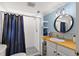 Bathroom featuring a walk-in shower, wood countertop, decorative mirror and a blue accent wall at 820 Hickory Ln, Palm Harbor, FL 34683