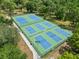 Aerial view of tennis courts with well-maintained green and blue courts surrounded by lush trees at 820 Hickory Ln, Palm Harbor, FL 34683