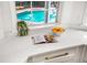 Kitchen counter with white countertops, a cookbook, a bowl of oranges, and a view of the blue pool at 101 Ponce De Leon Blvd, Belleair, FL 33756