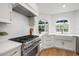 Bright kitchen features stainless steel appliances, a farmhouse sink, two arched windows and hardwood floors at 101 Ponce De Leon Blvd, Belleair, FL 33756