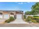 Townhome exterior with attached garages, concrete driveway, and landscaped garden featuring colorful flowers at 1116 Martin Luther King Jr Ave, Dunedin, FL 34698