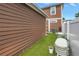 Exterior shot of the house shows brown siding and artificial turf in the backyard at 1116 Martin Luther King Jr Ave, Dunedin, FL 34698