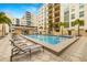 A community pool with several lounge chairs on the deck and nearby palm trees and other buildings at 1227 E Madison St # 902, Tampa, FL 33602