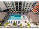 Aerial view of a community pool with lounge chairs and palm trees in a courtyard with the building complex at 1227 E Madison St # 902, Tampa, FL 33602