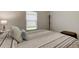 Neutral bedroom with a striped comforter, a bright window, and a decorative stool in the corner at 12407 Hilltop Farms Dr, Dade City, FL 33525