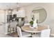 Open concept dining area with round wooden table, modern chairs, and views into the kitchen at 13084 Stillmont Pl, Tampa, FL 33624