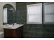 Stylish bathroom with green vertical tiles, wood vanity, a sleek mirror, and great natural light at 1606 S Arrawana Ave, Tampa, FL 33629