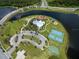 Aerial view of a community recreation area with a large pool, tennis courts, playground, and lush landscaping at 16313 Treasure Point Dr, Wimauma, FL 33598