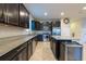 Modern kitchen featuring dark cabinets, stainless steel appliances, granite countertops, and an island with seating at 16313 Treasure Point Dr, Wimauma, FL 33598