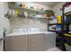 Efficient laundry room with modern washer, dryer, storage shelves, and cleaning supplies at 16313 Treasure Point Dr, Wimauma, FL 33598