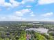 Overhead view displays a house nestled among trees, with a scenic lake nearby, under a vast, cloudy sky at 16411 Lake Byrd Dr, Tampa, FL 33618