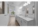 Bathroom featuring dual sinks, bright modern lighting, and light wood-look flooring at 17093 Moonflower Dr, Venice, FL 34293