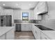 Modern kitchen with stainless steel appliances, white cabinets, a gray backsplash and hardwood floors at 17093 Moonflower Dr, Venice, FL 34293