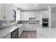Well-lit kitchen featuring stainless appliances, sleek white cabinets, a gray backsplash and hardwood floors at 17093 Moonflower Dr, Venice, FL 34293
