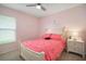 Bright bedroom featuring light pink walls and decor, complemented by a ceiling fan and large window at 17413 Garden Heath Ct, Land O Lakes, FL 34638