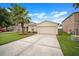 Charming single-story home with a two-car garage, palm tree, and well-manicured front lawn at 17413 Garden Heath Ct, Land O Lakes, FL 34638