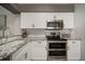 Well-appointed kitchen with modern appliances, white cabinetry, and granite countertops for meal preparation at 17413 Garden Heath Ct, Land O Lakes, FL 34638